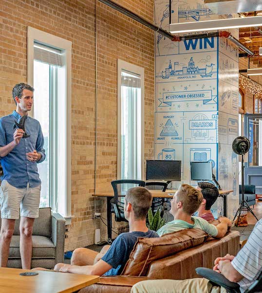 Ett antal personer i ett rum som verkar vara ett kreativt kontor. En av personerna står och berättar. Övriga sitter bekvämt. 